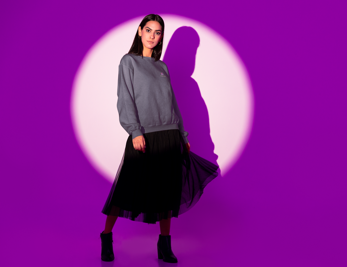 Amethyst After Hours Garment-Dyed Crewneck in Denim, worn by a woman in a spotlight against purple, with the Amethyst After Hours logo and portage.camp on the chest. Digital product mockup.