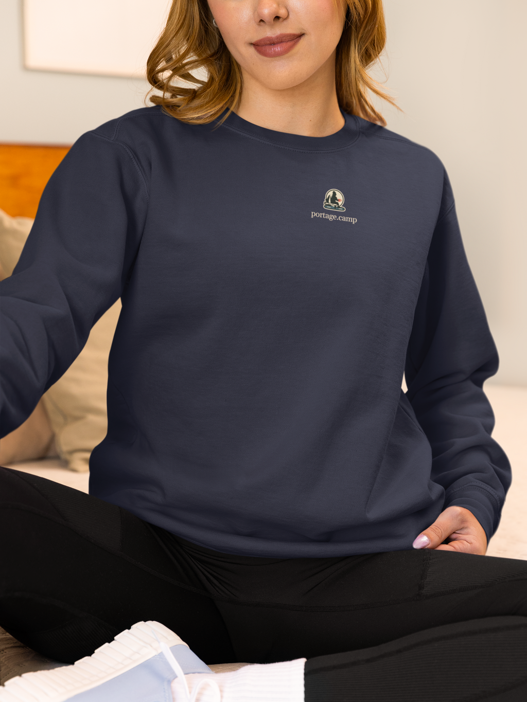 Quiet Hours Garment-Dyed Crewneck in True Navy, worn by a woman at home, with the Quiet Hours logo and portage.camp on the chest. Digital product mockup.