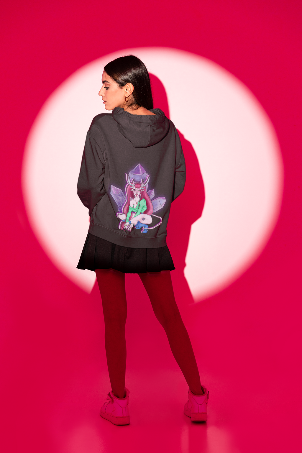 Amethyst After Hours Zip Hoodie in Black, worn by a woman seen from behind in a studio spotlight, showing the large print on the back. Digital product mockup.