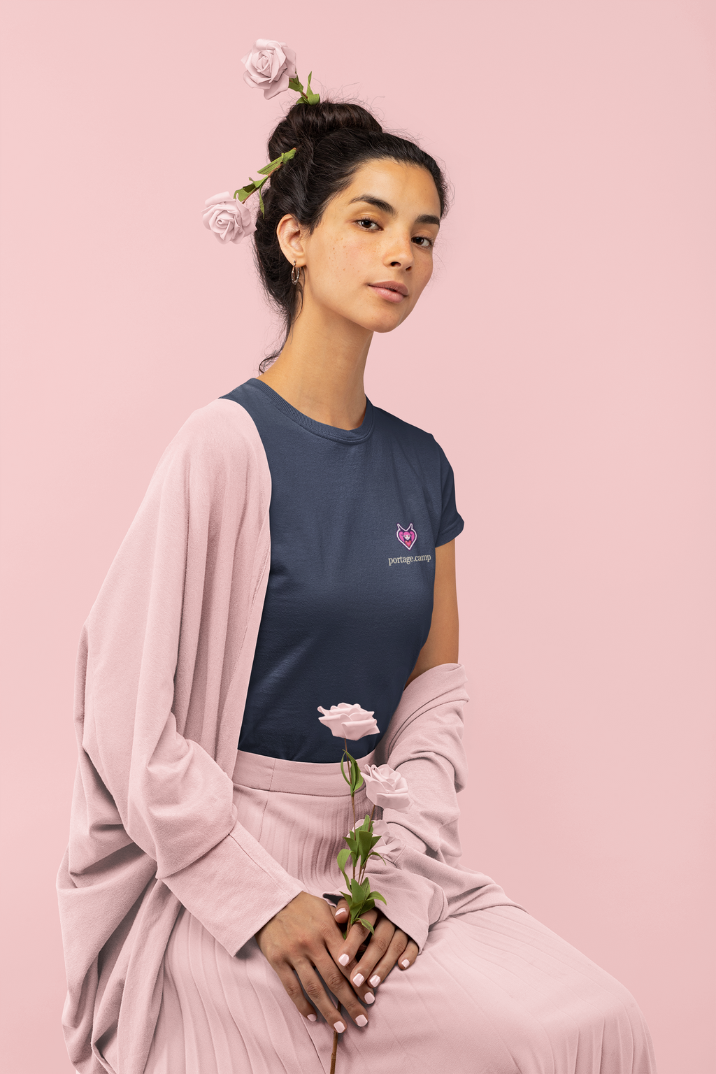 Heart Thief Women’s Relaxed Tee in Navy, worn by a woman holding a rose, with the Heart Thief logo and portage.camp on the chest. Digital product mockup.