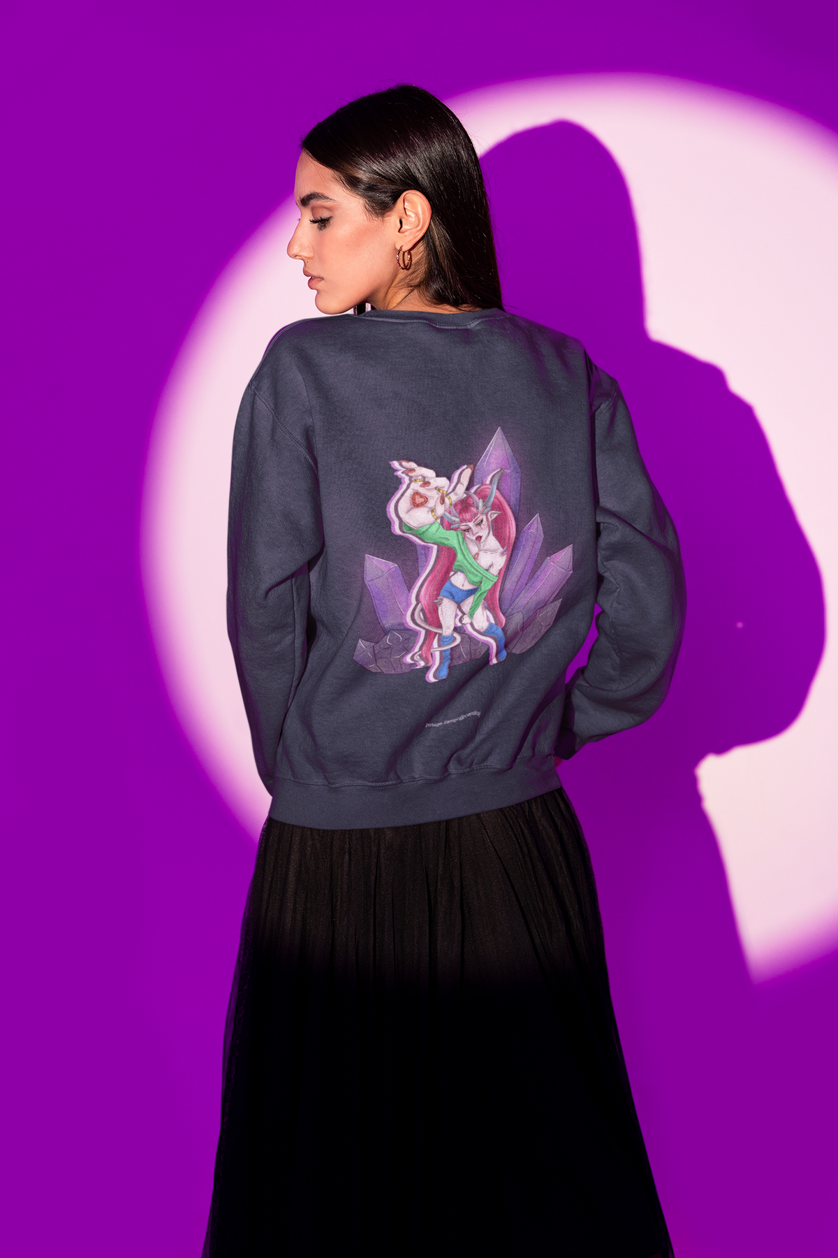 Amethyst After Hours Garment-Dyed Crewneck in True Navy, worn by a woman seen from behind in a studio under purple light, showing the large print on the back. Digital product mockup.