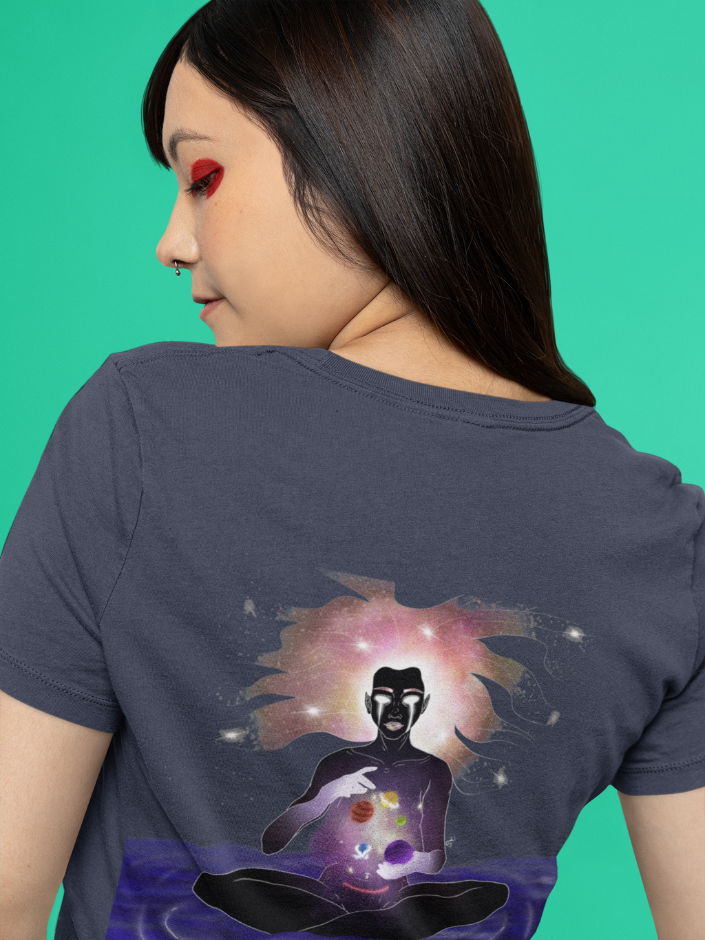 Orbit Keeper Women’s Relaxed Tee in Navy, worn by a woman seen from behind against green, showing the large print on the back. Digital product mockup.