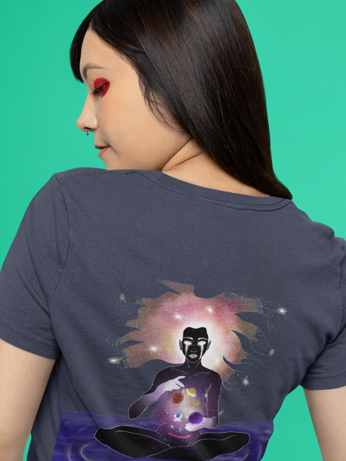Orbit Keeper Women’s Relaxed Tee in Navy, worn by a woman seen from behind against green, showing the large print on the back. Digital product mockup.