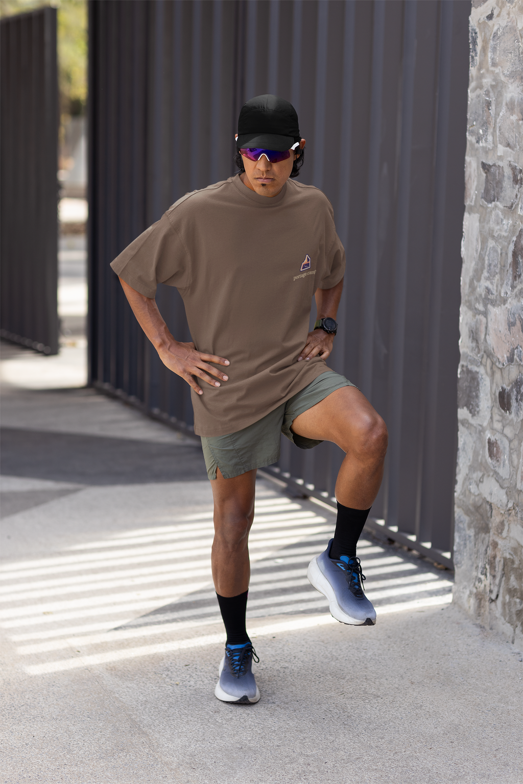 A Different Sky Garment-Dyed Tee in Espresso, worn by a man stretching before a run, with the A Different Sky logo and portage.camp on the chest. Digital product mockup.