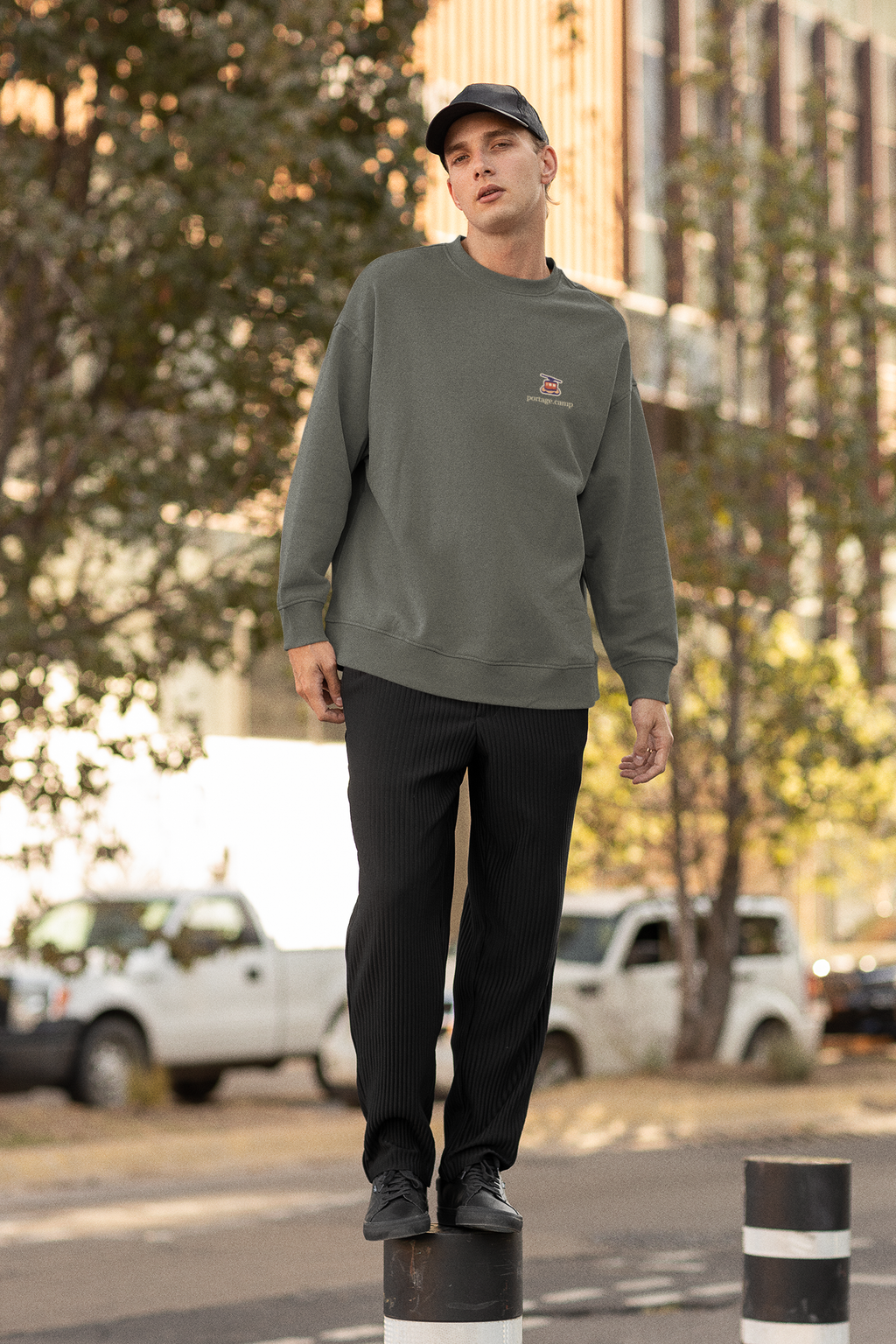 Cloud Ferry Garment-Dyed Crewneck in Pepper, worn by a man on a city street, with the Cloud Ferry logo and portage.camp on the chest. Digital product mockup.