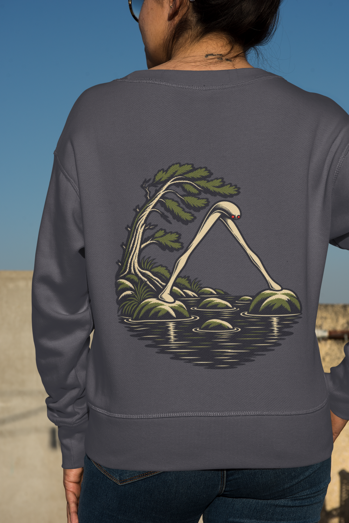 Small Hours Garment-Dyed Crewneck in Denim, worn by a woman seen from behind against a plain backdrop, showing the large print on the back. Digital product mockup.