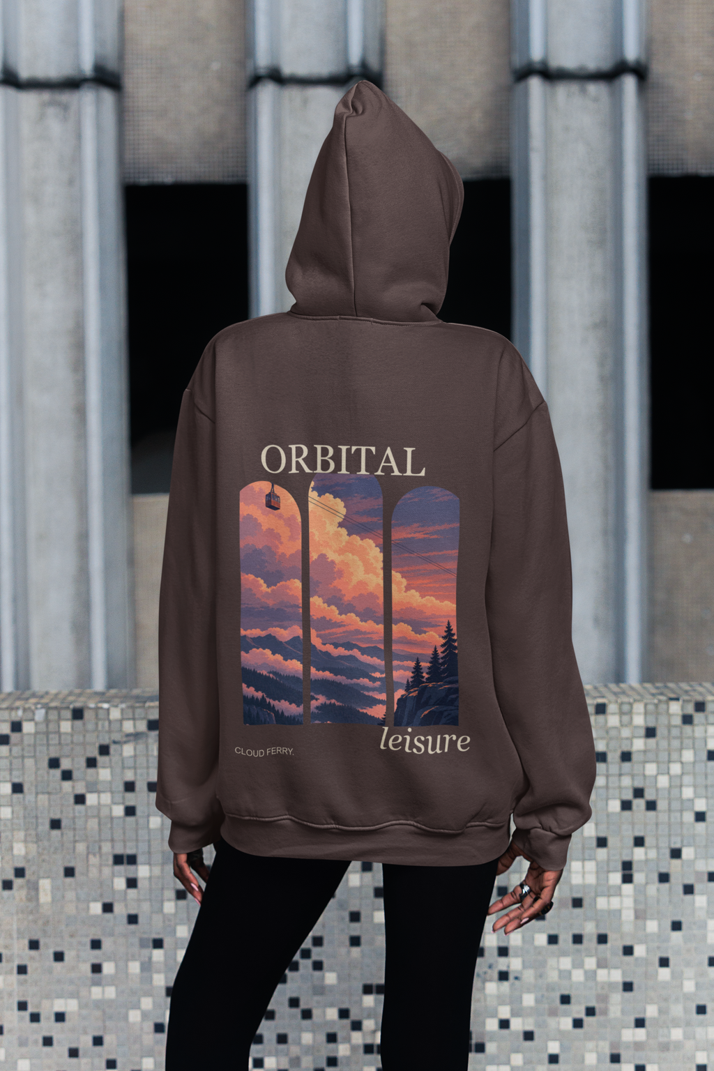 Edge of Evening Heavyweight Hoodie in Brown, worn by a woman seen from behind on a city sidewalk, showing the large print on the back. Digital product mockup.