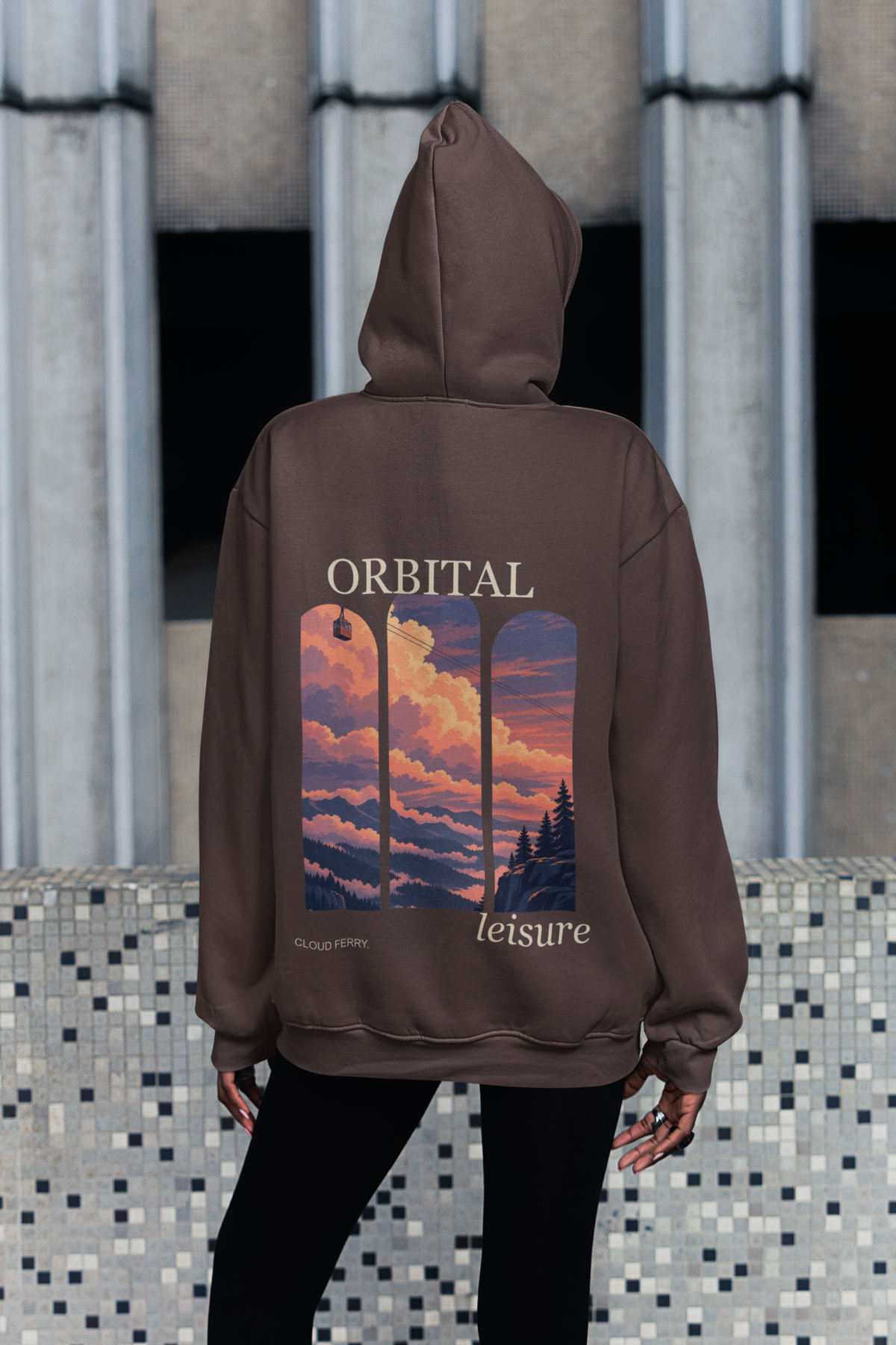 Edge of Evening Heavyweight Hoodie in Brown, worn by a woman seen from behind on a city sidewalk, showing the large print on the back. Digital product mockup.