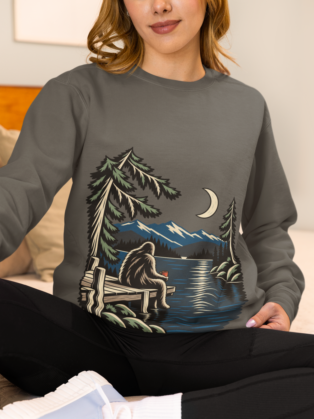 Quiet Hours Garment-Dyed Crewneck (Front Print) in Pepper, worn by a woman at home, showing the large print on the front. Digital product mockup.