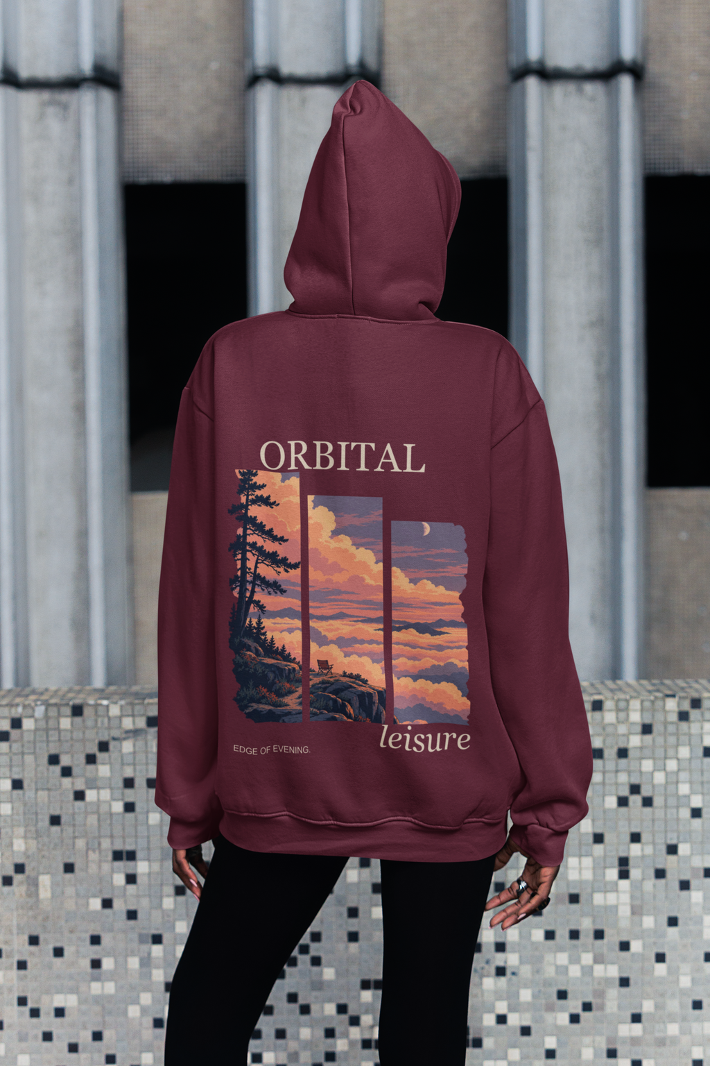 Edge of Evening Midweight Hoodie in Maroon, worn by a woman seen from behind on a city sidewalk, showing the large print on the back. Digital product mockup.