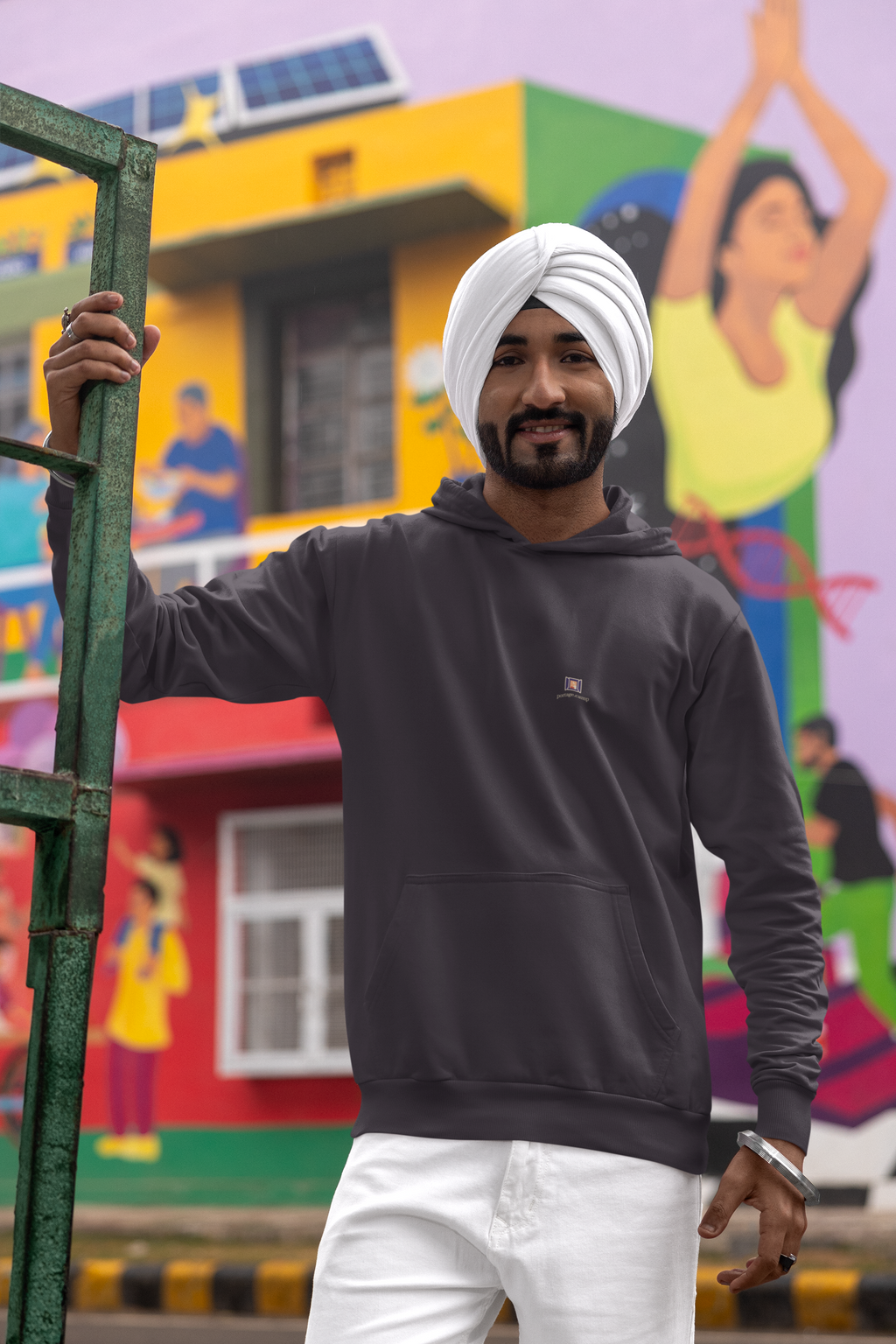 Open Late Midweight Hoodie in Black, worn by a man in a turban on a busy street, with the Open Late logo and portage.camp on the chest. Digital product mockup.