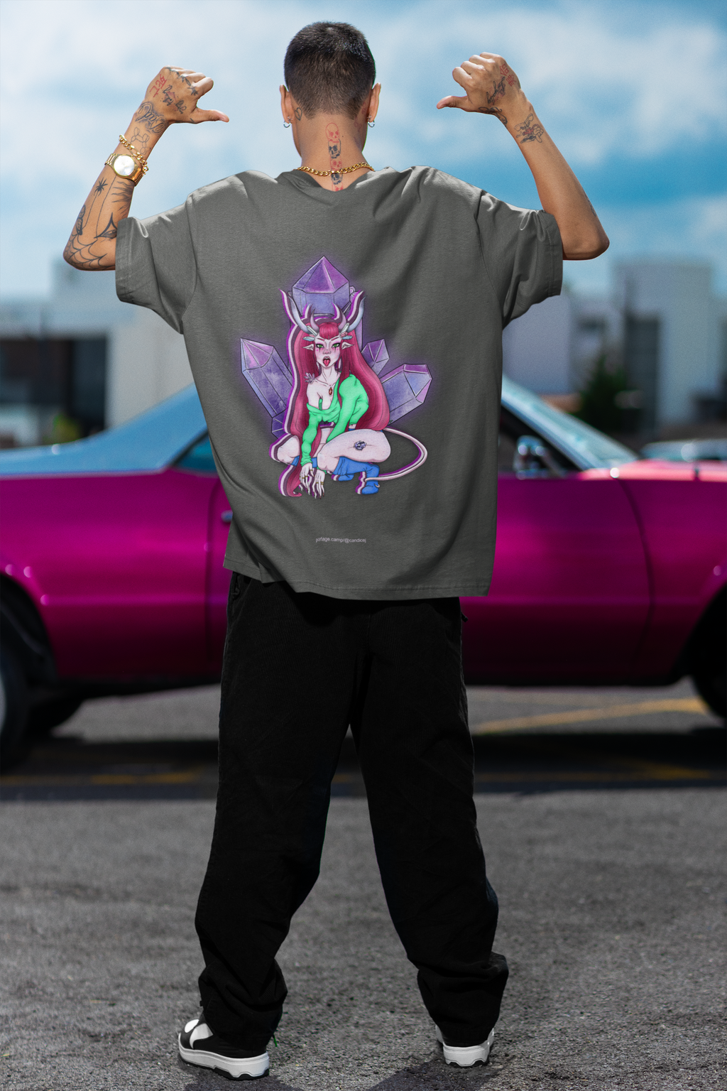 Amethyst After Hours Garment-Dyed Tee in Pepper, worn by a man seen from behind by a pink car, showing the large print on the back. Digital product mockup.