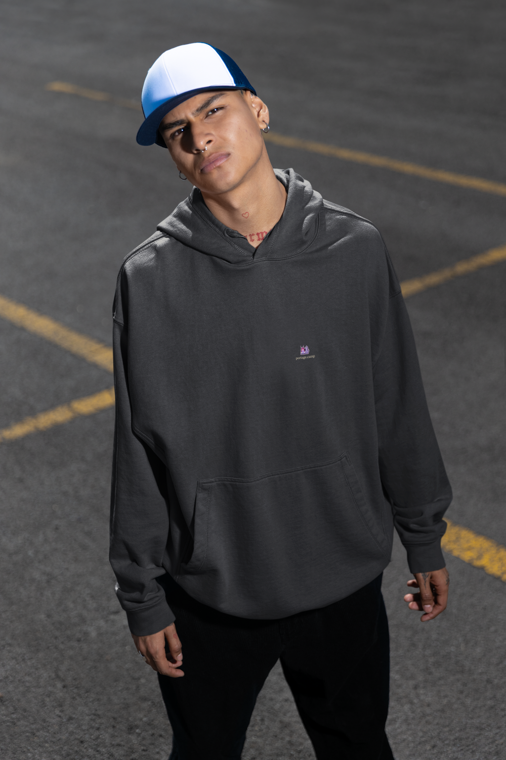 Amethyst After Hours Heavyweight Hoodie in Black, worn by a man in a parking lot, with the Amethyst After Hours logo and portage.camp on the left chest. Digital product mockup.