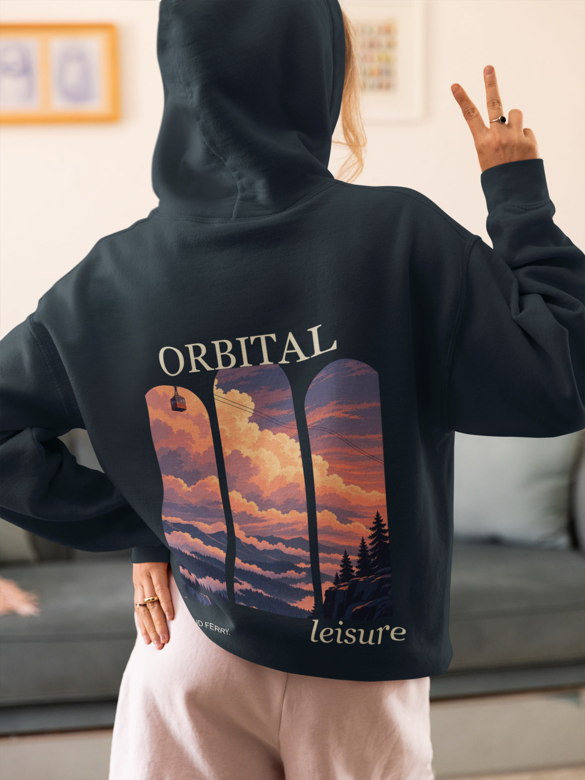 Cloud Ferry Midweight Hoodie in Classic Navy, worn by a woman seen from behind at home, making a peace sign, showing the large print on the back. Digital product mockup.