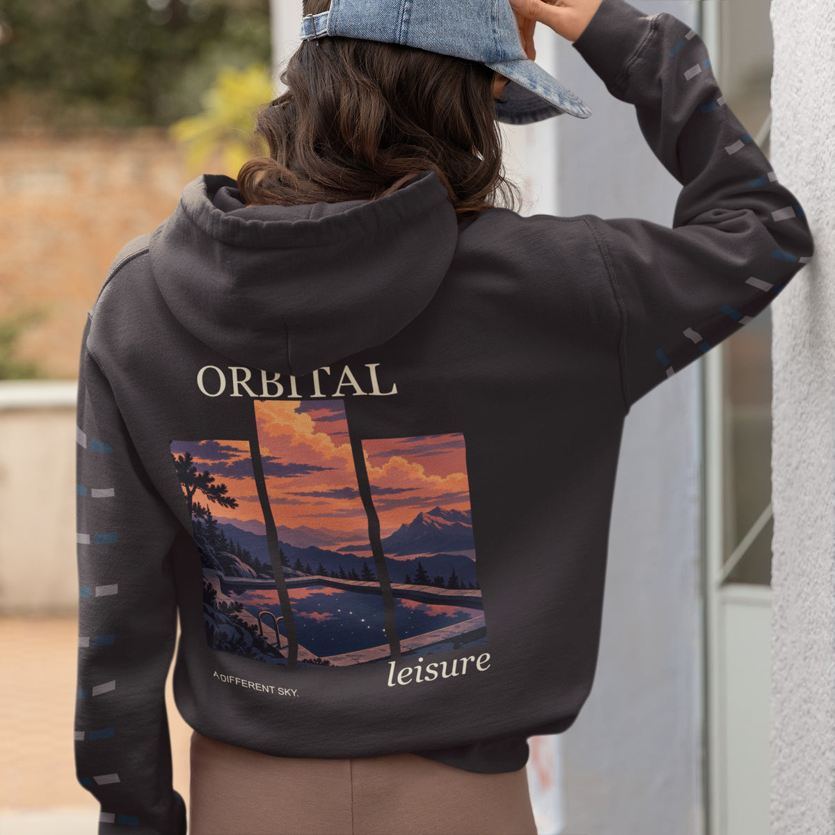 A Different Sky Midweight Hoodie in Black, worn by a woman seen from behind at home, showing the large print on the back. Digital product mockup.