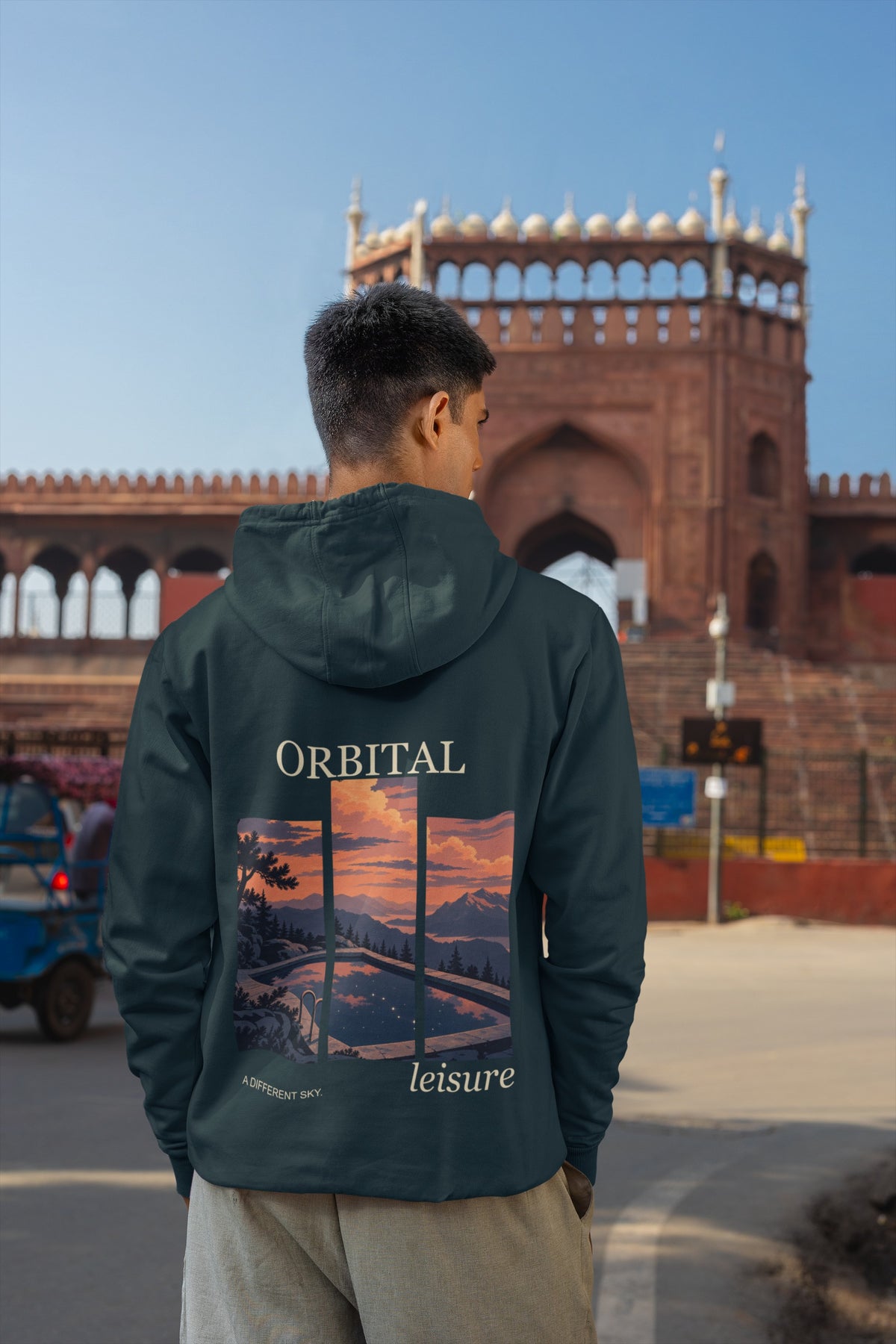 A Different Sky Midweight Hoodie in Classic Navy, worn by a man seen from behind on a city street, showing the large print on the back. Digital product mockup.