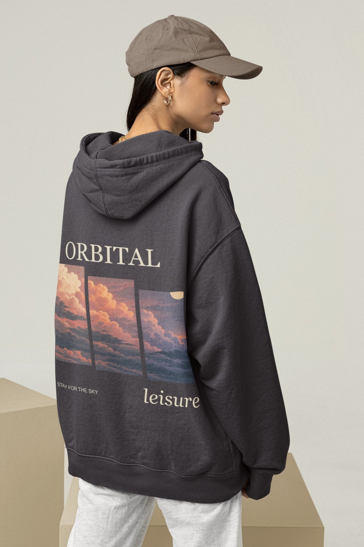 Stay for the Sky Midweight Hoodie in Black, worn by a woman seen from behind in a studio, showing the large print on the back. Digital product mockup.
