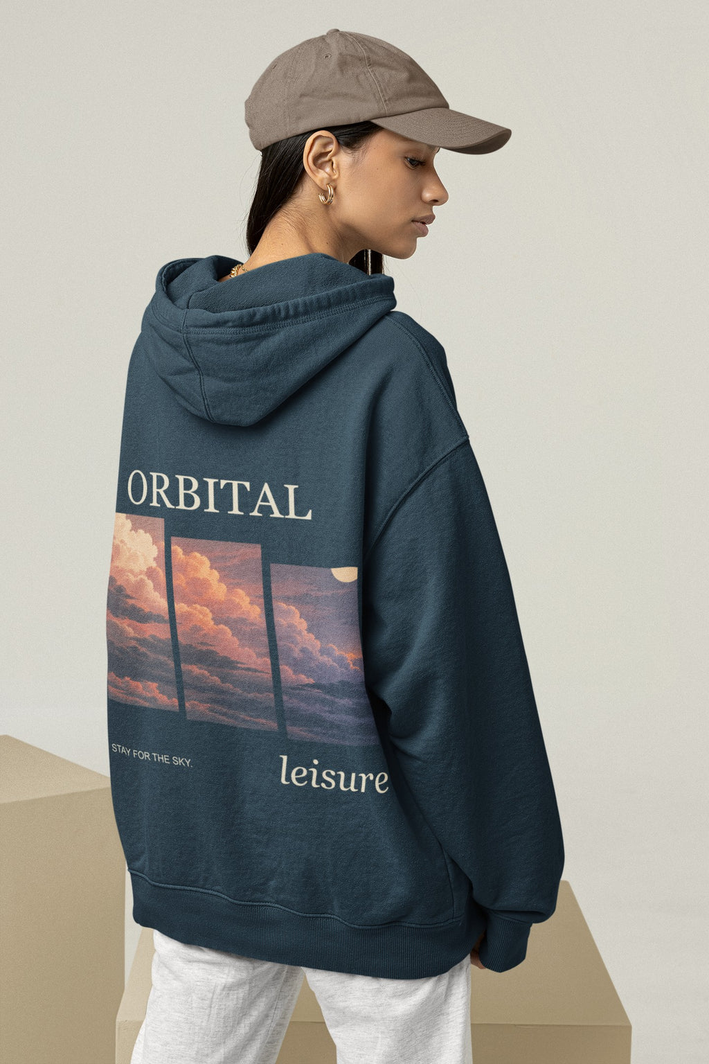 Stay for the Sky Midweight Hoodie in Classic Navy, worn by a woman seen from behind in a studio, showing the large print on the back. Digital product mockup.