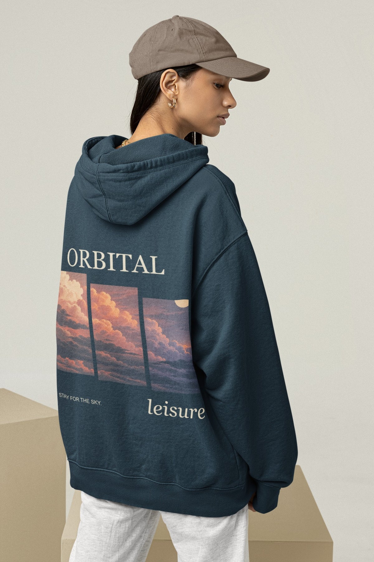 Stay for the Sky Midweight Hoodie in Classic Navy, worn by a woman seen from behind in a studio, showing the large print on the back. Digital product mockup.