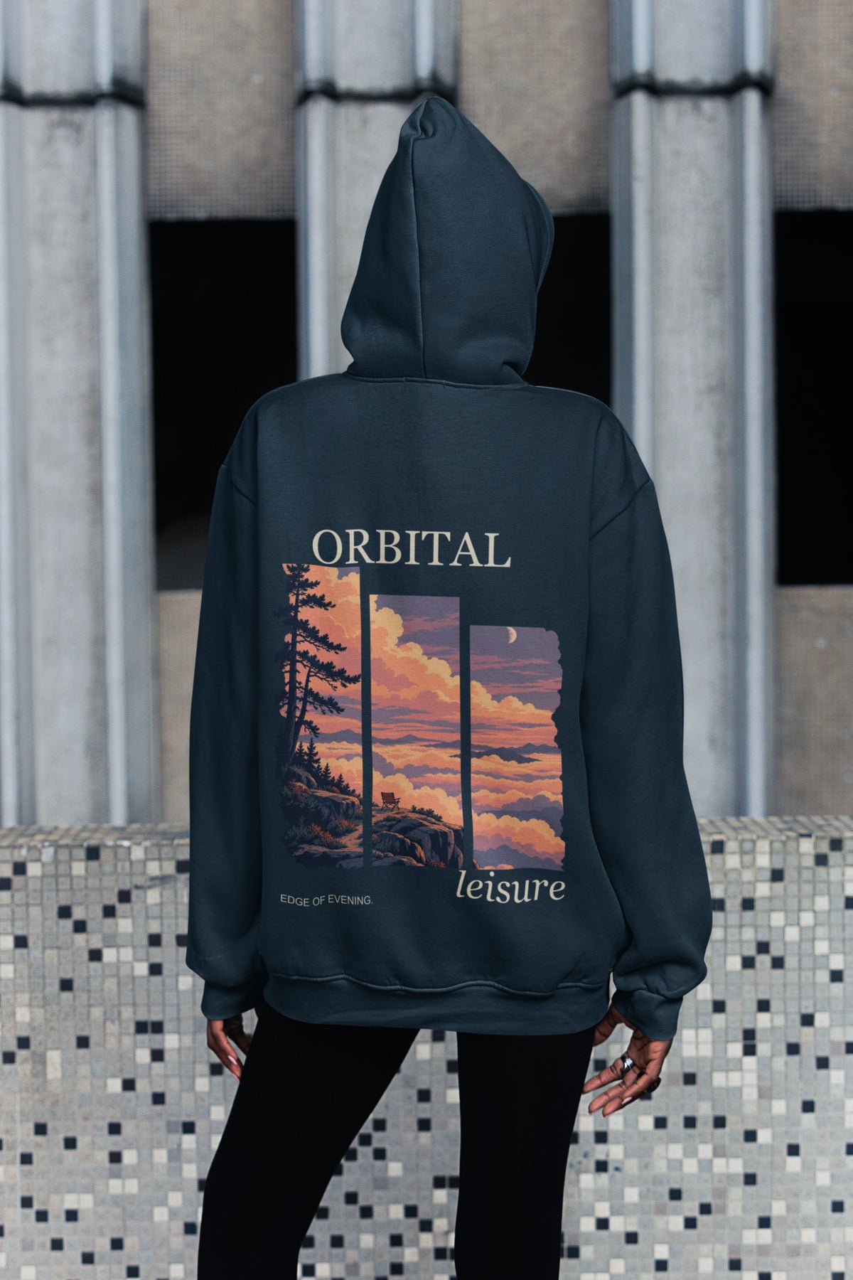 Edge of Evening Midweight Hoodie in Classic Navy, worn by a woman seen from behind on a city sidewalk, showing the large print on the back. Digital product mockup.