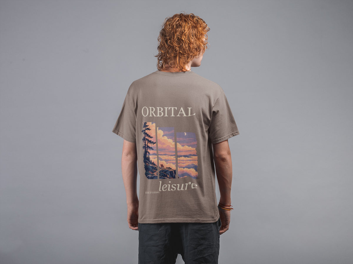 Edge of Evening Garment-Dyed Tee in Espresso, worn by a man seen from behind against a plain grey wall, showing the large print on the back. Digital product mockup.
