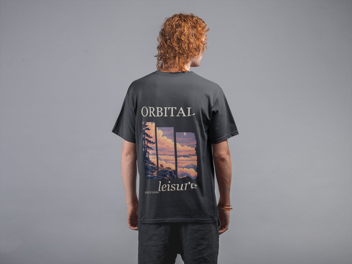 Edge of Evening Garment-Dyed Tee in Black, worn by a man seen from behind against a plain grey wall, showing the large print on the back. Digital product mockup.