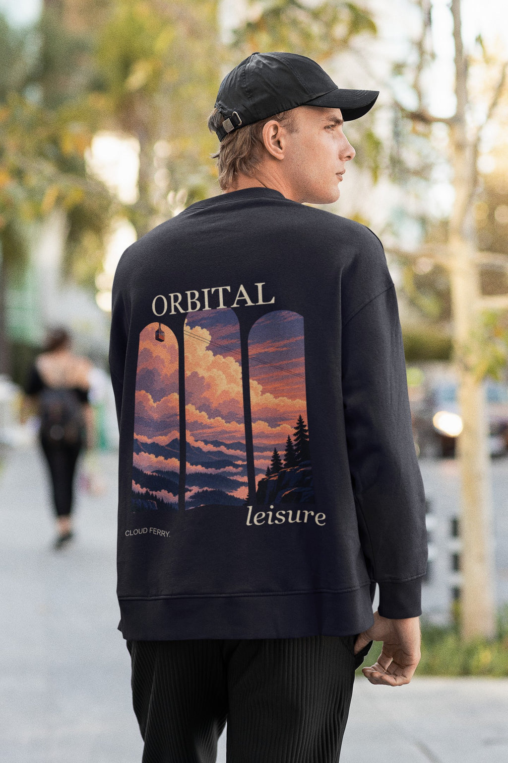 Cloud Ferry Garment-Dyed Crewneck in True Navy, worn by a man seen from behind walking down a city street, showing the large print on the back. Digital product mockup.
