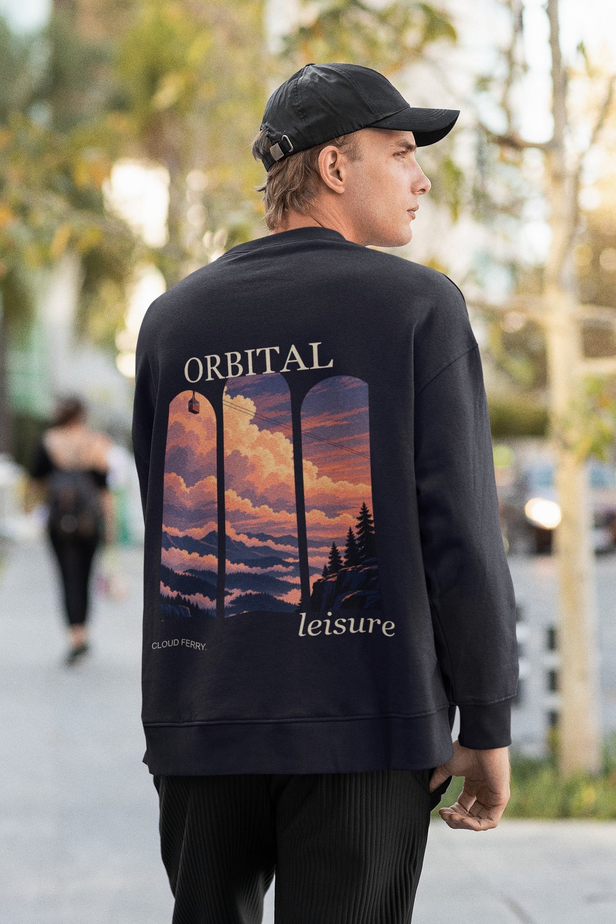 Cloud Ferry Garment-Dyed Crewneck in True Navy, worn by a man seen from behind walking down a city street, showing the large print on the back. Digital product mockup.