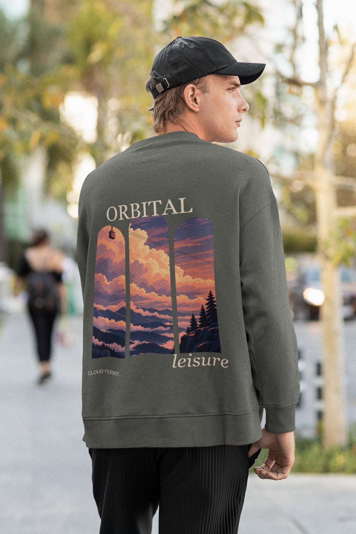 Cloud Ferry Garment-Dyed Crewneck in Pepper, worn by a man seen from behind walking down a city street, showing the large print on the back. Digital product mockup.