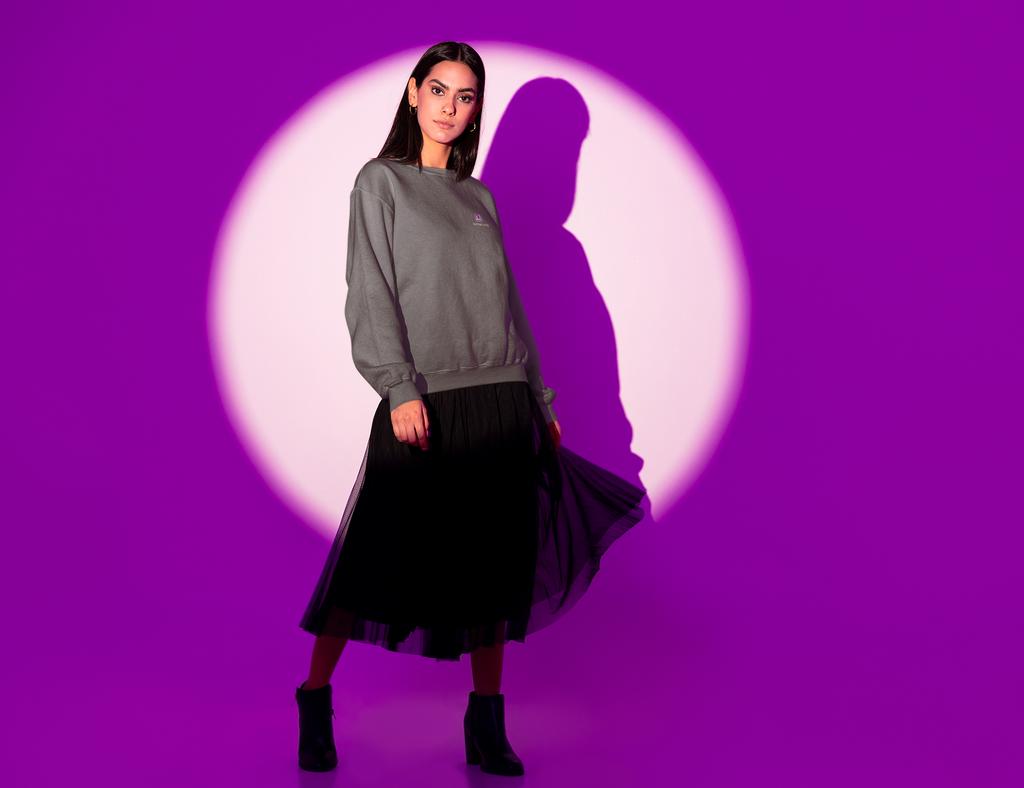 Amethyst After Hours Garment-Dyed Crewneck in Pepper, worn by a woman in a spotlight against purple, with the Amethyst After Hours logo and portage.camp on the chest. Digital product mockup.
