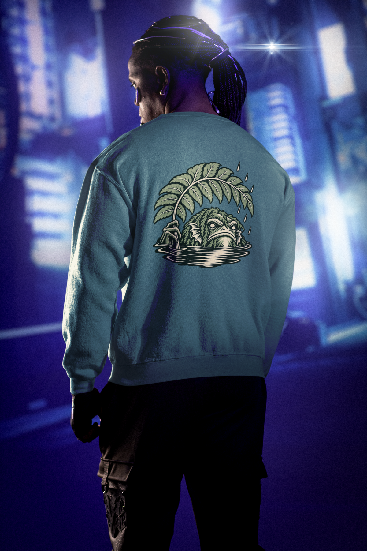 Rain Check Garment-Dyed Crewneck in Blue Spruce, worn by a man seen from behind under neon city lights, showing the large print on the back. Digital product mockup.