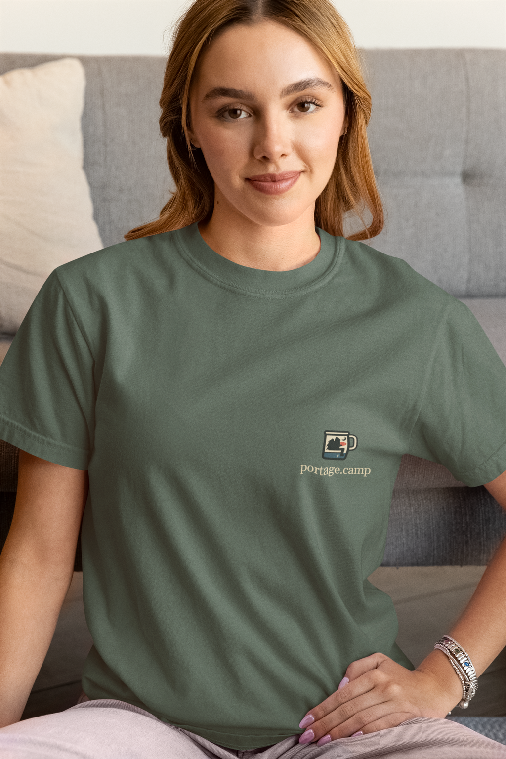 Quiet Hours Garment-Dyed Tee in Blue Spruce, worn by a woman at home, with the Quiet Hours logo and portage.camp on the chest. Digital product mockup.