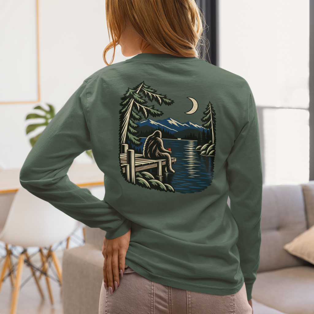 Quiet Hours Garment-Dyed Long-Sleeve Tee in Blue Spruce, worn by a woman seen from behind at home, showing the large print on the back. Digital product mockup.