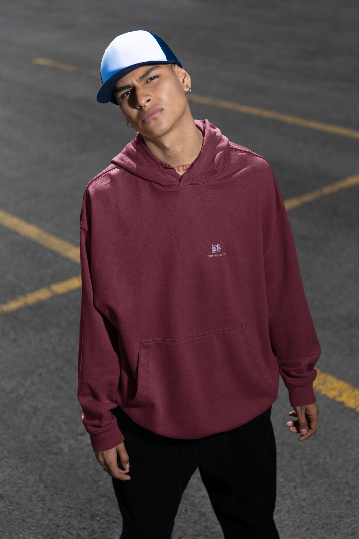 Amethyst After Hours Midweight Hoodie in Maroon, worn by a man in a parking lot, with the Amethyst After Hours logo and portage.camp on the chest. Digital product mockup.