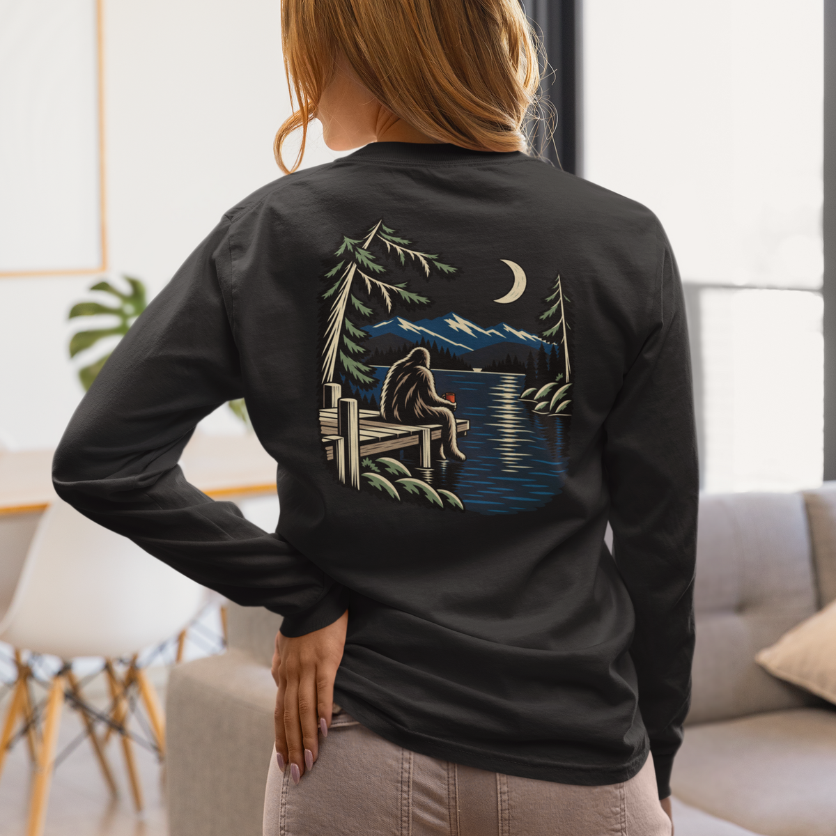 Quiet Hours Garment-Dyed Long-Sleeve Tee in Black, worn by a woman seen from behind at home, showing the large print on the back. Digital product mockup.