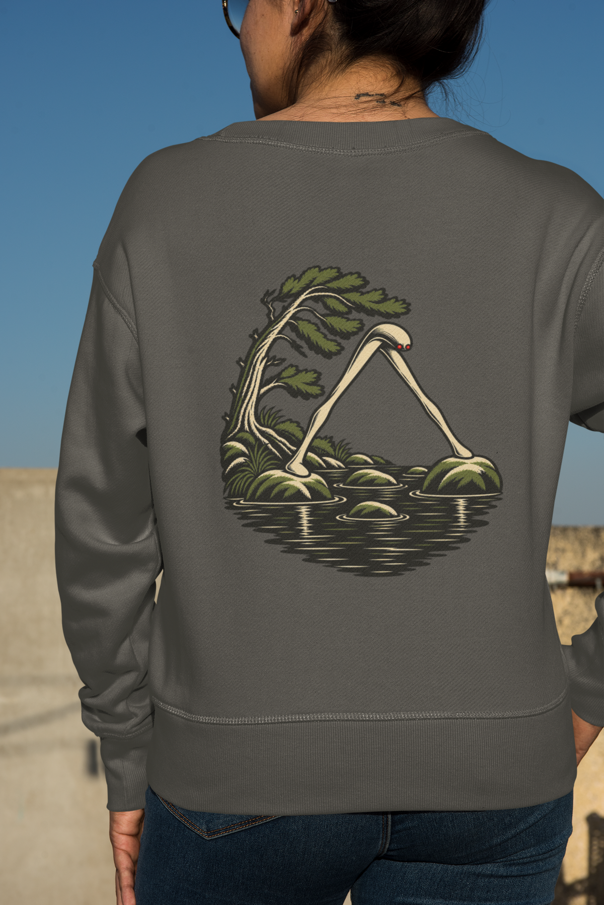 Small Hours Garment-Dyed Crewneck in Pepper, worn by a woman seen from behind against a plain backdrop, showing the large print on the back. Digital product mockup.