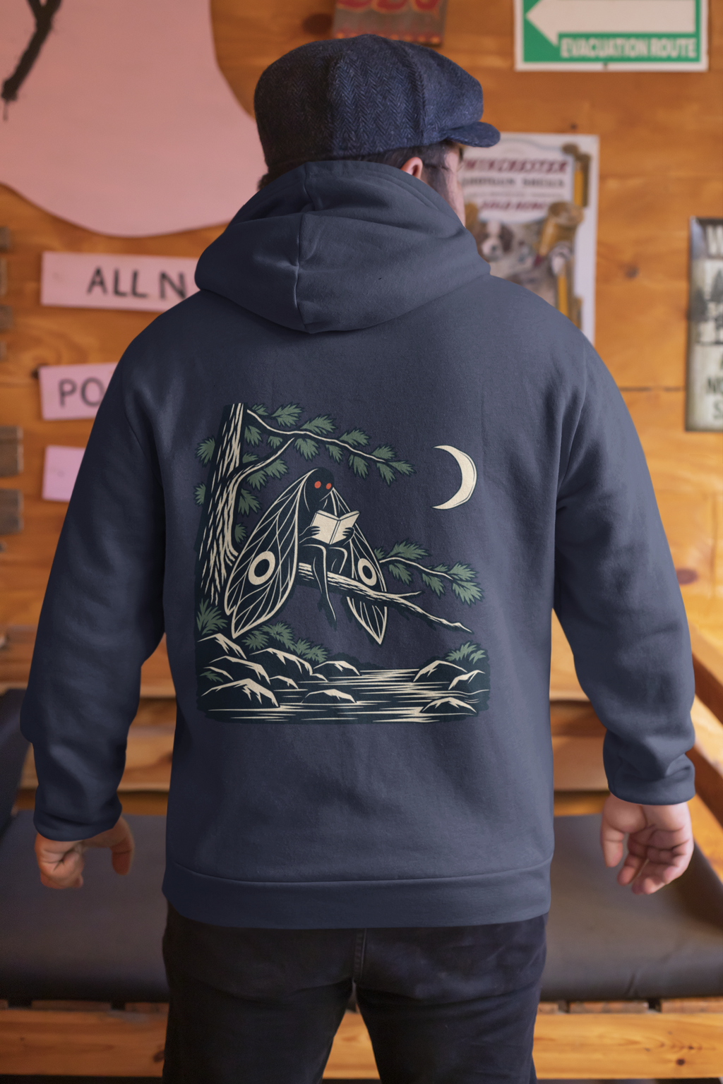 Night Library Zip Hoodie in Navy, worn by a man seen from behind in a wood-panelled bar, showing the large print on the back. Digital product mockup.