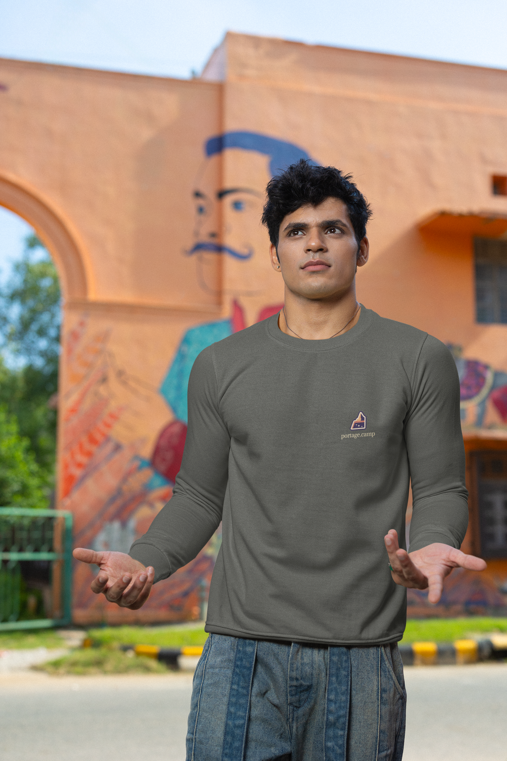 A Different Sky Garment-Dyed Crewneck in Pepper, worn by a man on a city street, with the A Different Sky logo and portage.camp on the chest. Digital product mockup.