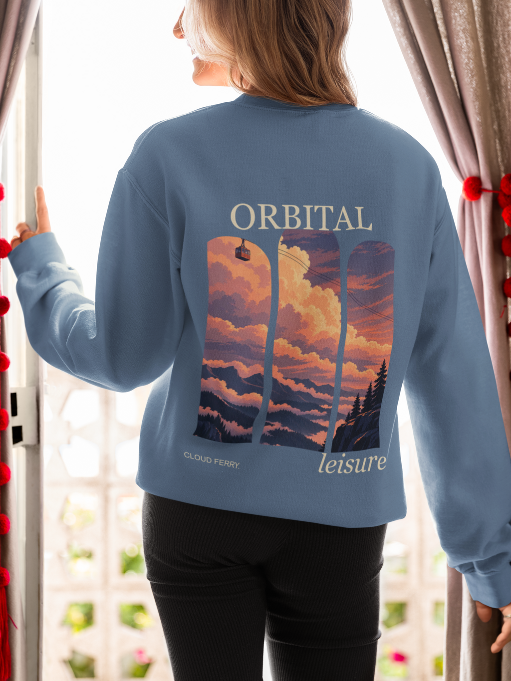 Cloud Ferry Garment-Dyed Crewneck in Blue Jean, worn by a woman seen from behind at an open door, showing the large print on the back. Digital product mockup.