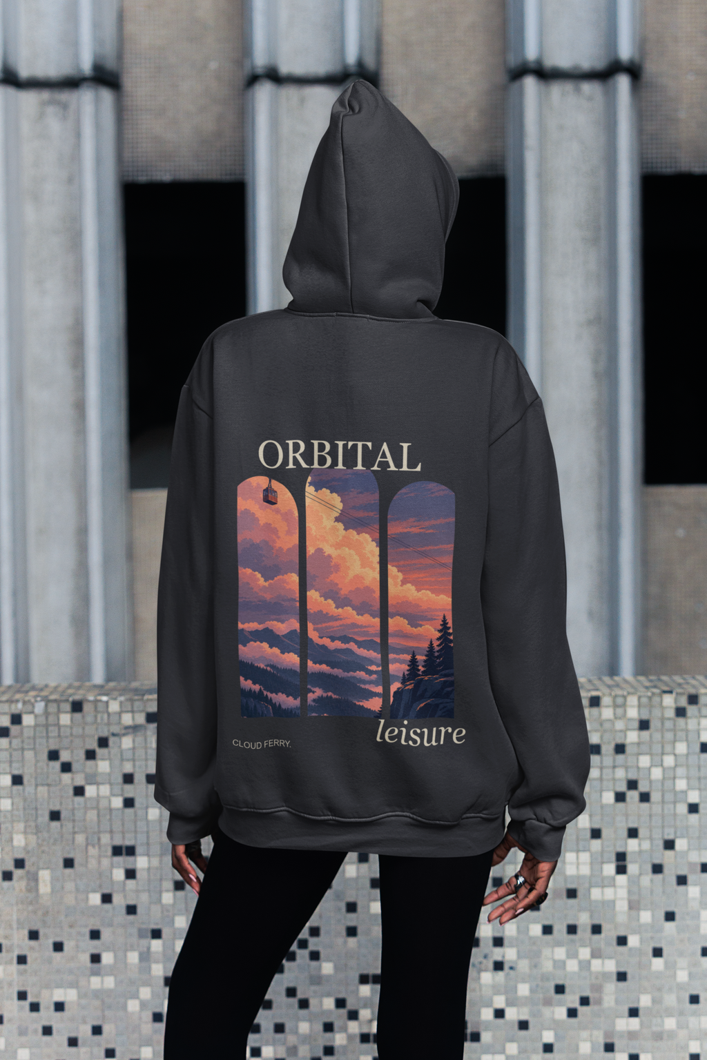 Edge of Evening Heavyweight Hoodie in Black, worn by a woman seen from behind on a city sidewalk, showing the large print on the back. Digital product mockup.