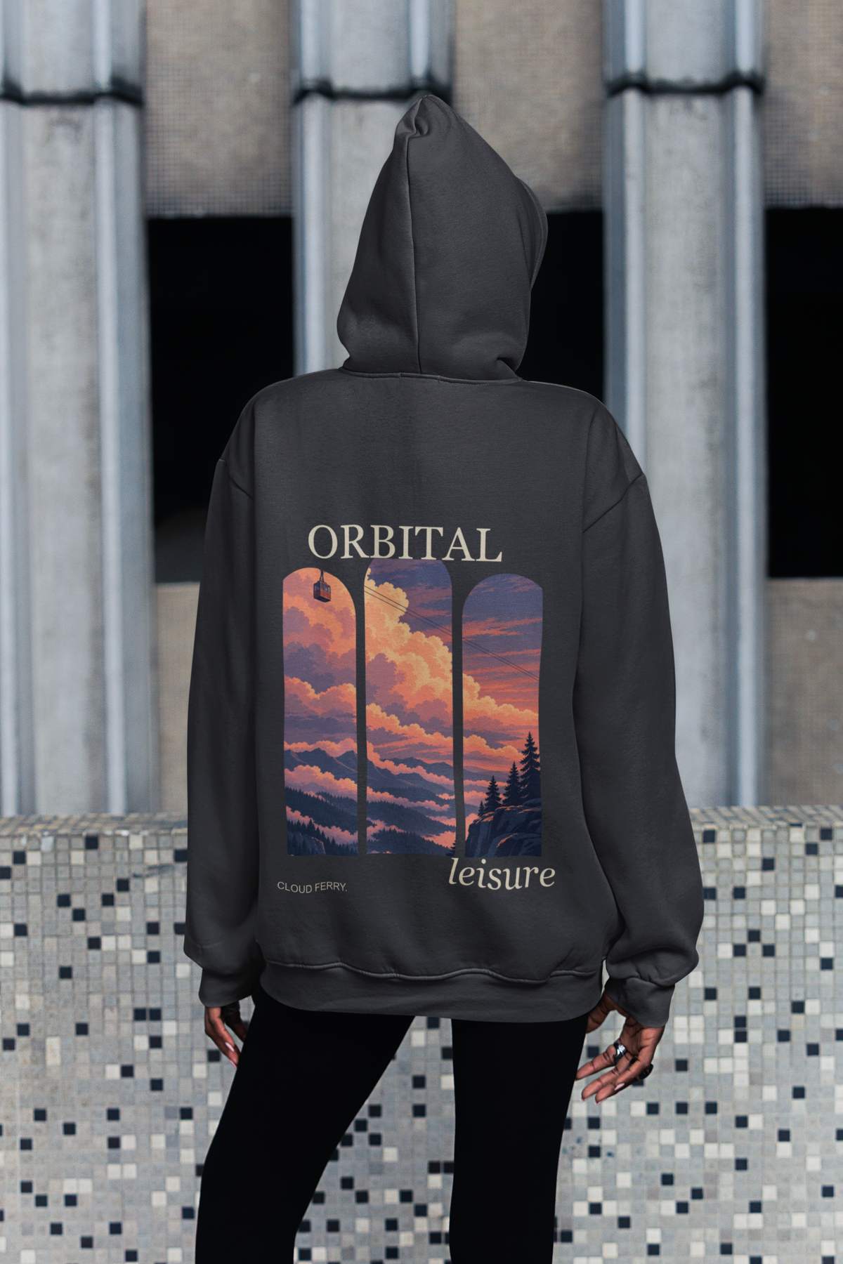 Edge of Evening Heavyweight Hoodie in Black, worn by a woman seen from behind on a city sidewalk, showing the large print on the back. Digital product mockup.