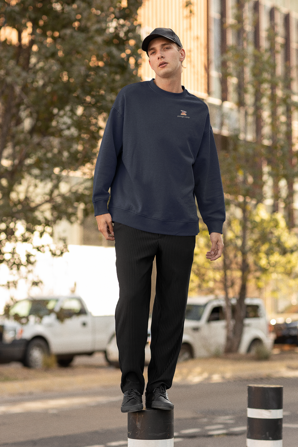 Cloud Ferry Garment-Dyed Crewneck in True Navy, worn by a man on a city street, with the Cloud Ferry logo and portage.camp on the chest. Digital product mockup.