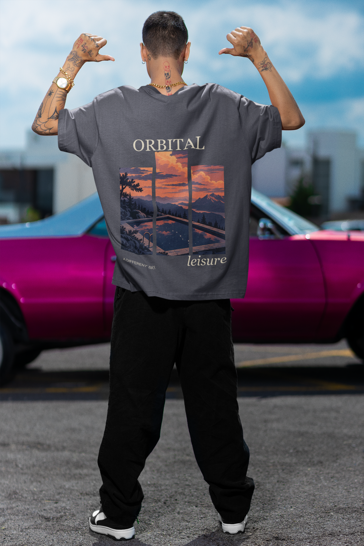 Amethyst After Hours Garment-Dyed Tee in Navy, worn by a man seen from behind by a pink car, showing the large print on the back. Digital product mockup.