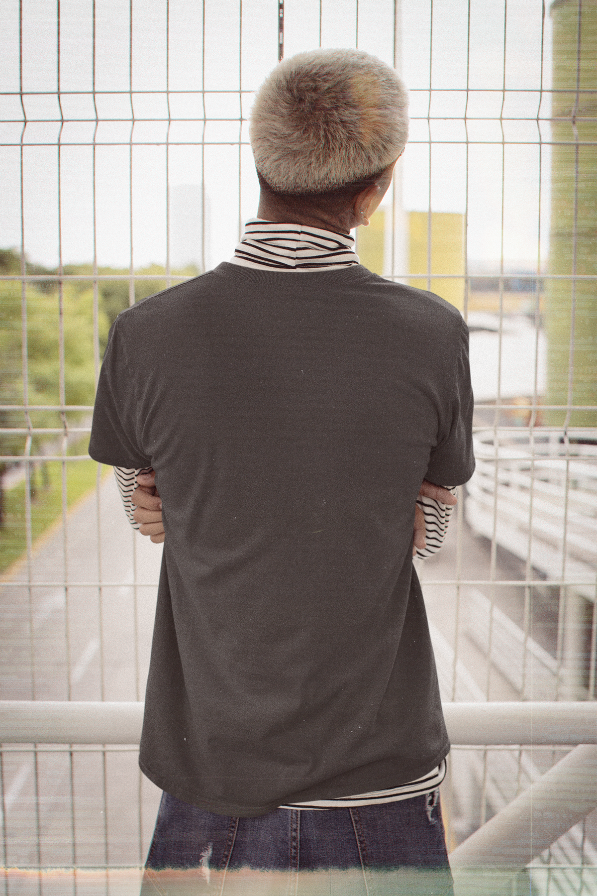 Orbit Keeper Garment-Dyed Tee in Black, worn by a man seen from behind in a nineties grunge outfit, showing the large print on the back. Digital product mockup.