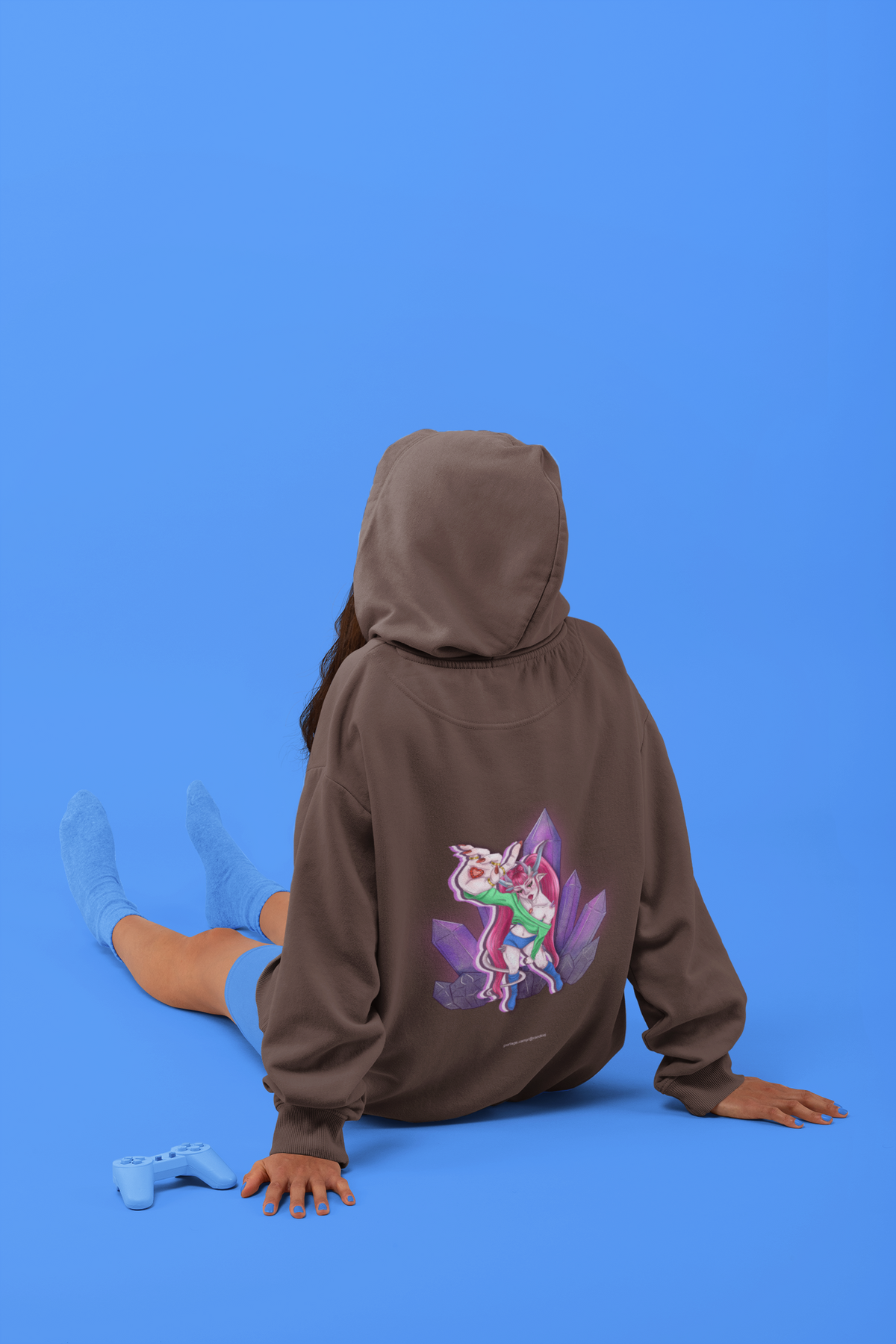 Rain Check Heavyweight Hoodie in Brown, worn by a woman seen from behind seated on a studio floor, showing the large print on the back. Digital product mockup.