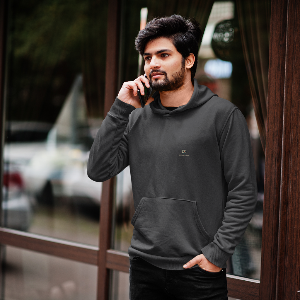 Quiet Hours Heavyweight Hoodie in Black, worn by a man by a café window, on a phone call, with the Quiet Hours logo and portage.camp on the left chest. Digital product mockup.