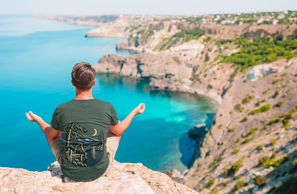 Quiet Hours Garment-Dyed Tee in Blue Spruce, worn by a man seen from behind on a misty mountain top, showing the large print on the back. Digital product mockup.