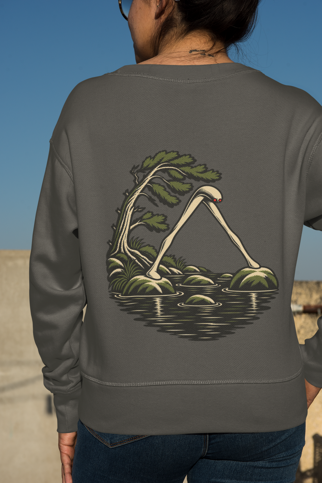 Small Hours Garment-Dyed Crewneck in Pepper, worn by a woman seen from behind against a plain backdrop, showing the large print on the back. Digital product mockup.
