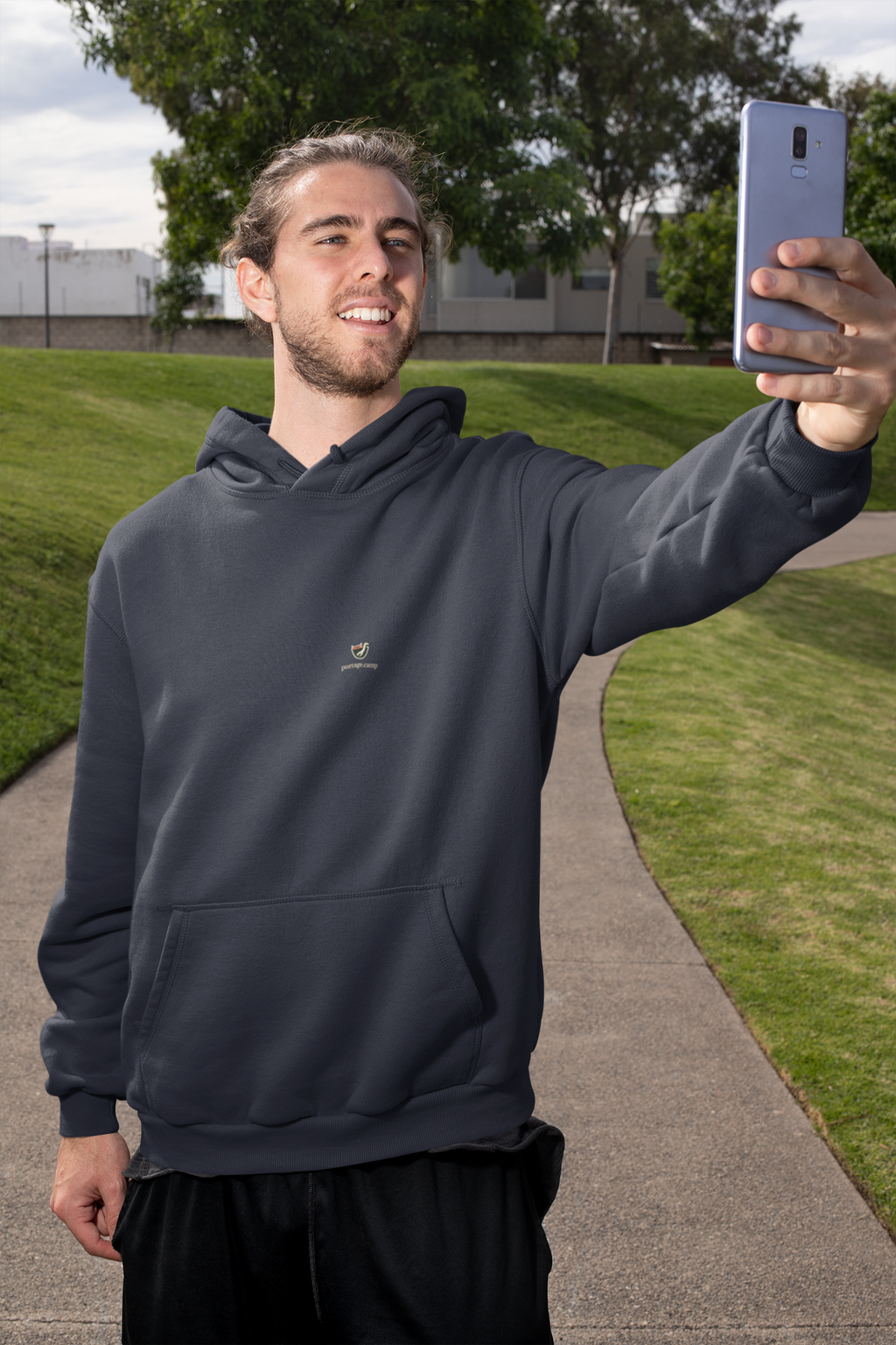 Seen Briefly Midweight Hoodie in Classic Navy, worn by a man taking a selfie on a city street, with the Seen Briefly logo and portage.camp on the chest. Digital product mockup.