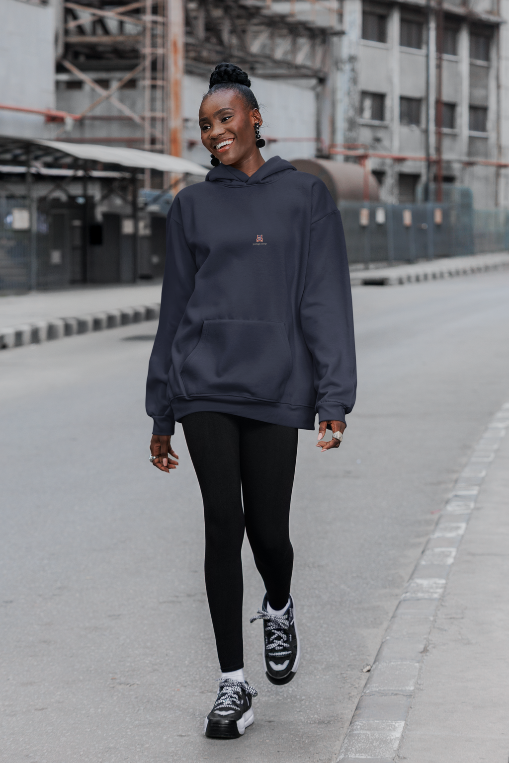 Edge of Evening Midweight Hoodie in Classic Navy, worn by a woman walking down a city street, with the Edge of Evening logo and portage.camp on the chest. Digital product mockup.